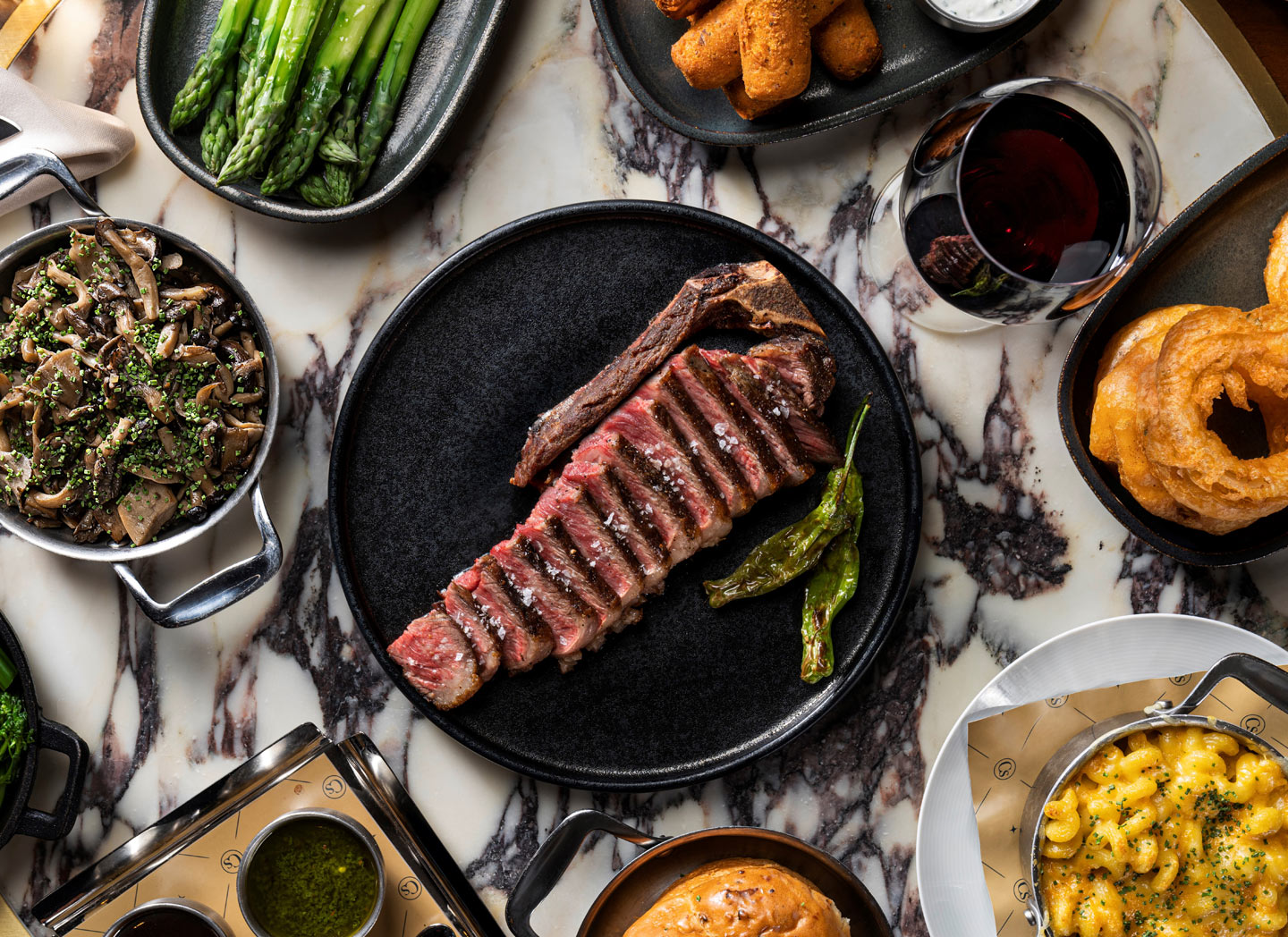 Steak, sides and wine on a marble table at Carversteak
